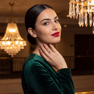 Woman in a green dress with red lipstick posing indoors with chandeliers in the background