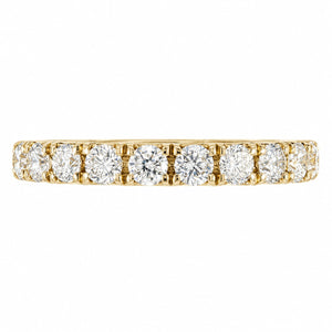A yellow gold eternity ring featuring a row of round brilliant-cut diamonds set in a prong style, shown against a plain white background.
