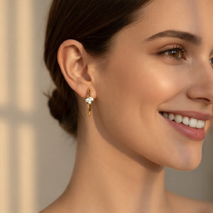Close-up of a woman wearing gold earrings with a neutral background