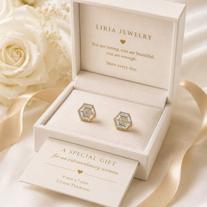 Gold earrings in a LIRIA JEWELRY box with white roses in the background