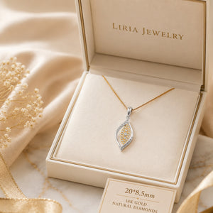 A silver and gold teardrop pendant necklace with small clear stones, displayed in an open cream-colored jewelry box. The brand name 'LIRIA JEWELRY' is printed inside the lid.