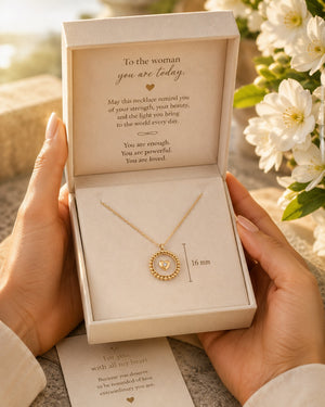 Gold necklace in a decorative box with a heartfelt message, held by a person.