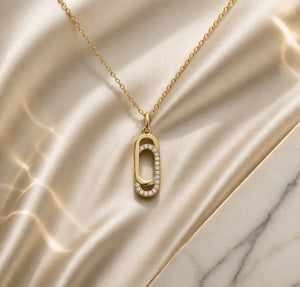 Gold necklace with a unique pendant on a marble surface