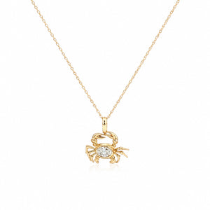 Delicate yellow gold necklace featuring a crab-shaped pendant with a sparkling oval diamond centerpiece, suspended from a fine chain on a light gray background.