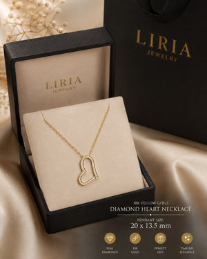 A gold heart-shaped diamond necklace displayed inside an open black LIRIA Jewelry box on a beige cushion, with a black LIRIA bag and gift box in the background. Text at the bottom reads '18K YELLOW GOLD DIAMOND HEART NECKLACE' and 'PENDANT SIZE 20 x 13.