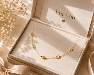 Gold necklace in a jewelry box with 'For you' card and flowers.