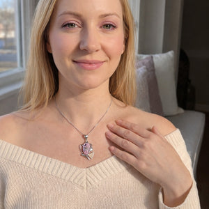Woman wearing a necklace with a pink pendant indoors