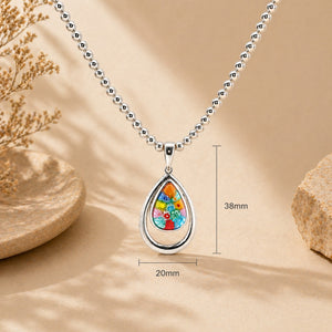 Necklace with a colorful teardrop pendant on a beige background