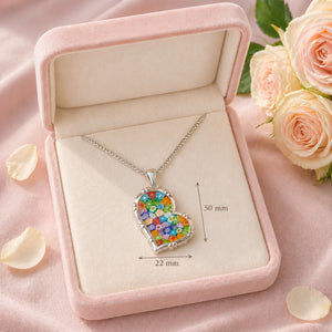 Heart-shaped colorful pendant necklace in a pink jewelry box with roses and petals.