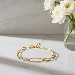 Gold bracelet on a marble surface with white flowers in the background