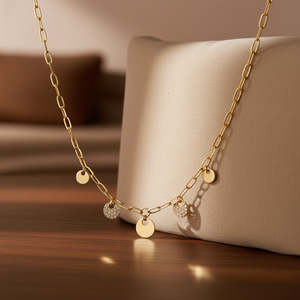 Gold chain necklace with round pendants on a wooden surface