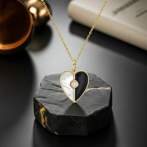 Heart-shaped pendant necklace with black and white design on a dark stone surface