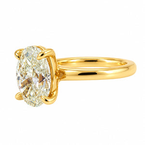 An oval-cut diamond ring set in a polished yellow gold band with a four-prong setting, shown on a plain white background.
