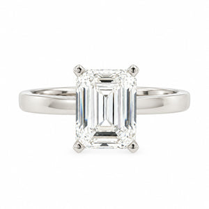 An emerald-cut diamond engagement ring in a polished silver-colored metal band, set against a plain white background.
