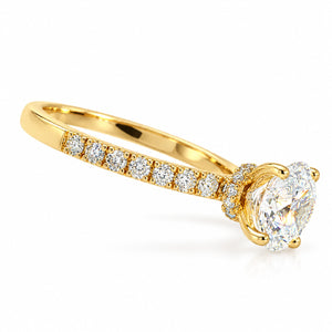 A yellow gold solitaire engagement ring featuring a large oval-cut diamond center stone and a row of smaller round diamonds along the band, set against a clean white background.