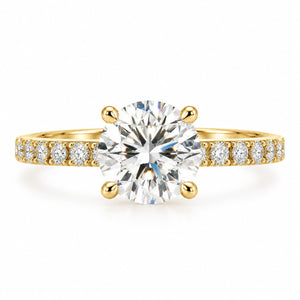 A yellow gold solitaire engagement ring featuring a large round brilliant-cut center stone, with a pavé-set band adorned with smaller round diamonds, shown on a clean white background.