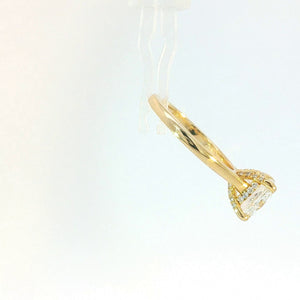 A yellow gold ring with a cushion-cut clear gemstone and small accent stones, shown hanging from a clear display stand against a white background.