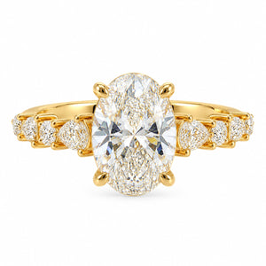 A yellow gold ring featuring a large oval-cut diamond center stone with smaller round and marquise-cut diamonds set along the shoulders, shown on a plain white background.