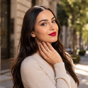 Woman with red lipstick and a beige sweater standing on a street.