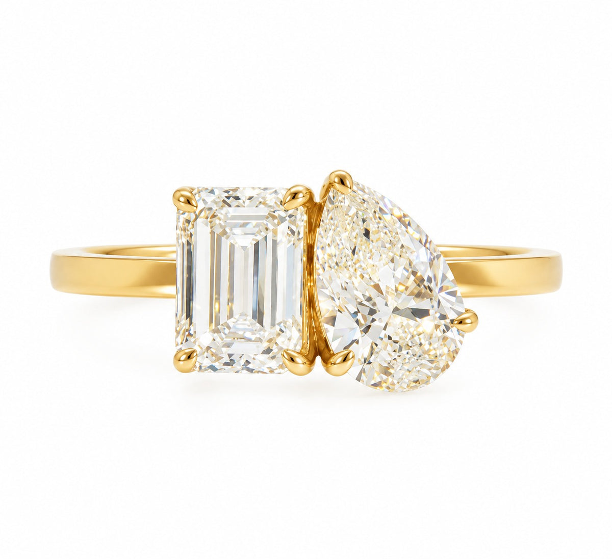 A yellow gold ring featuring an emerald-cut diamond on the left and a pear-cut diamond on the right, set against a plain white background.
