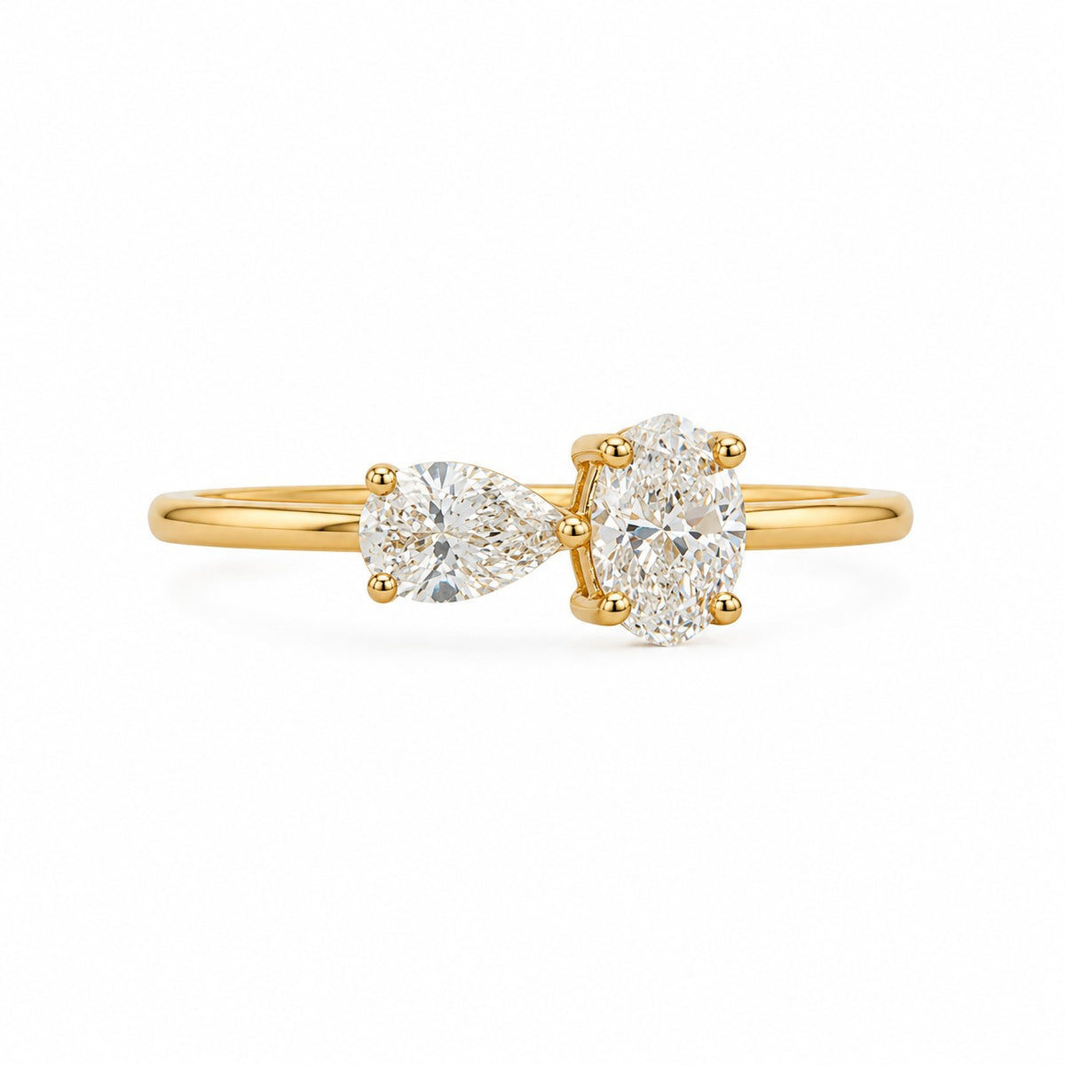 A yellow gold ring featuring a pear-cut diamond on the left and a round brilliant-cut diamond on the right, set on a polished gold band against a clean white background.