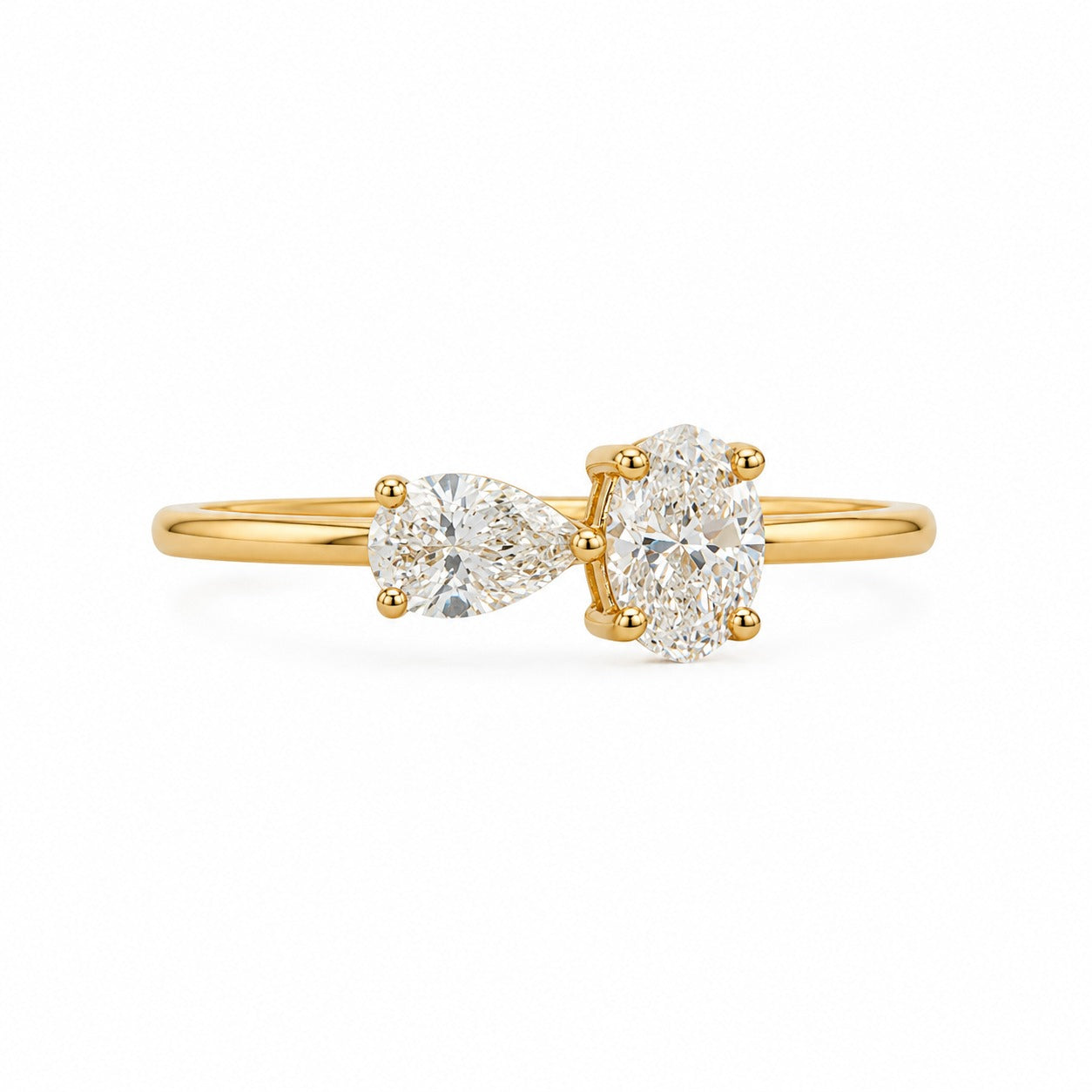 A yellow gold ring featuring a pear-cut diamond on the left and a round brilliant-cut diamond on the right, set on a polished gold band against a clean white background.