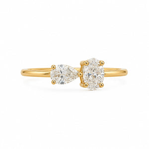 A yellow gold ring featuring a pear-cut diamond on the left and a round brilliant-cut diamond on the right, set on a polished gold band against a clean white background.