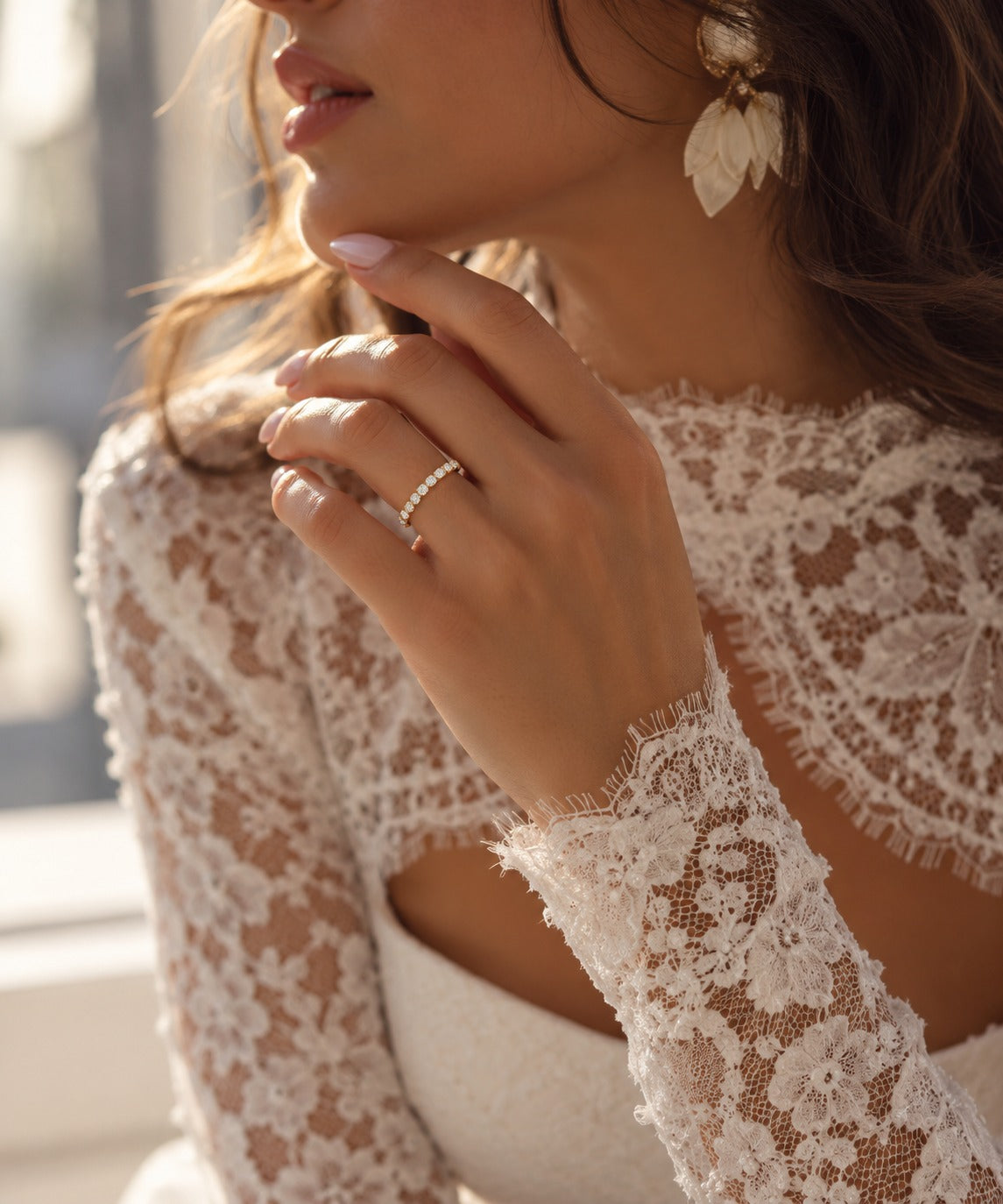 Close-up of a bride wearing a 14K yellow gold wedding band featuring 17 round lab-grown diamonds totaling 0.23 CT, with her hand near her face and an elegant lace wedding dress.