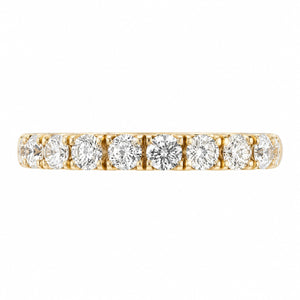A yellow gold eternity ring featuring a row of round-cut clear gemstones, presented on a solid white background.