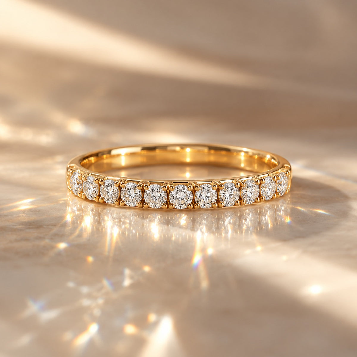 A gold eternity ring set with round brilliant-cut diamonds, resting on a shimmering gold surface with dramatic light reflections.