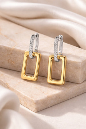 Gold and silver earrings on a beige stone surface