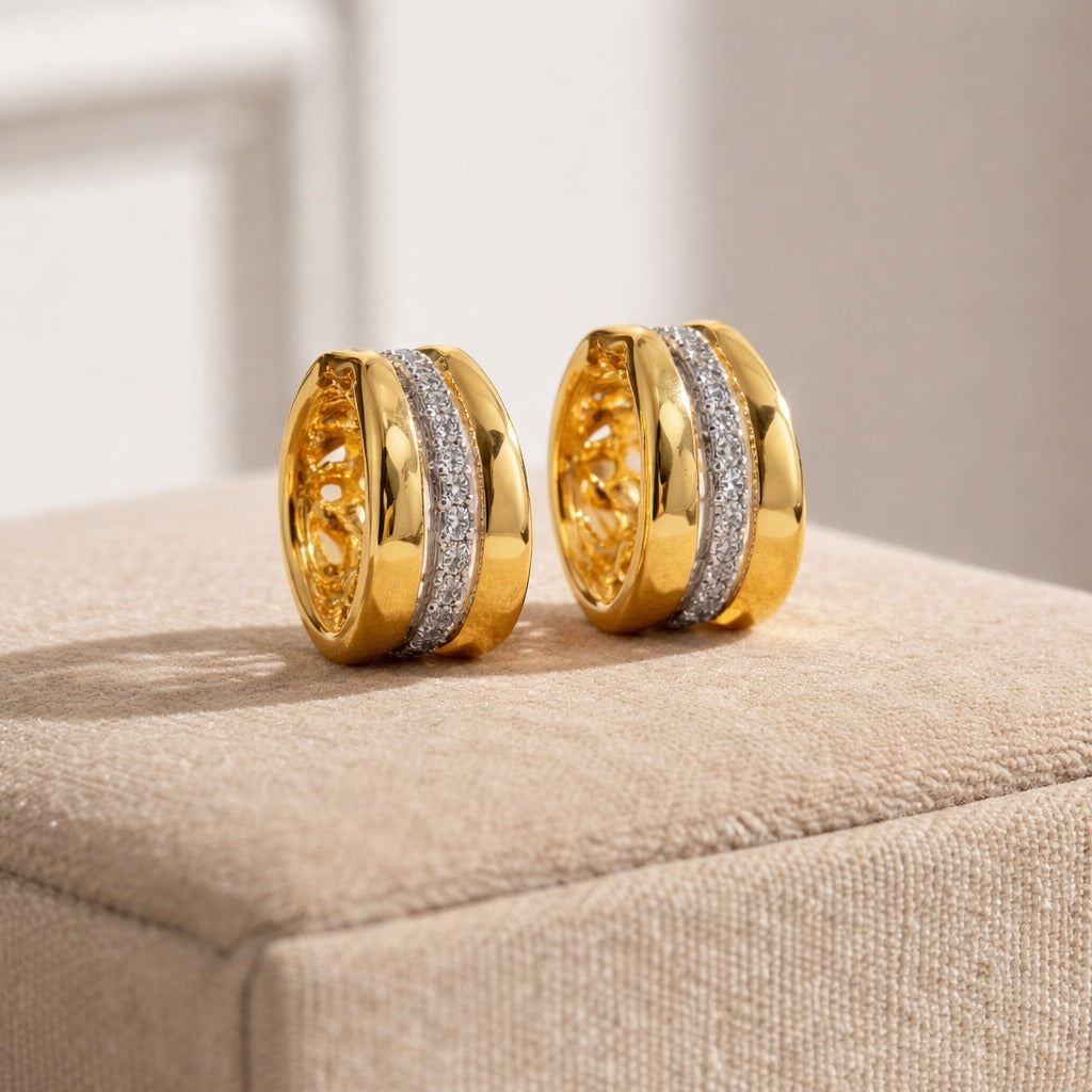 Gold hoop earrings with diamond accents on a beige surface