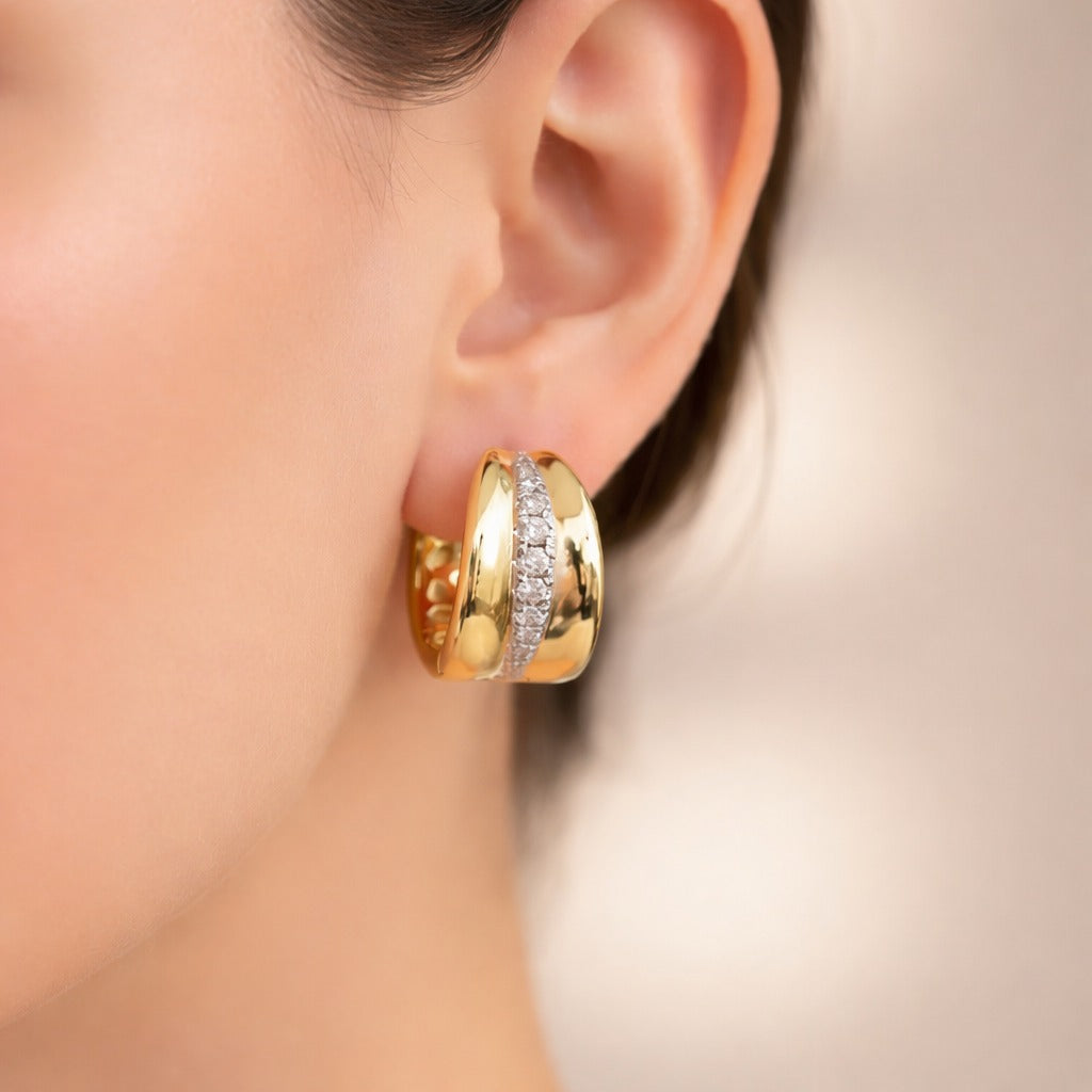 Gold hoop earrings with embedded diamonds on a blurred background