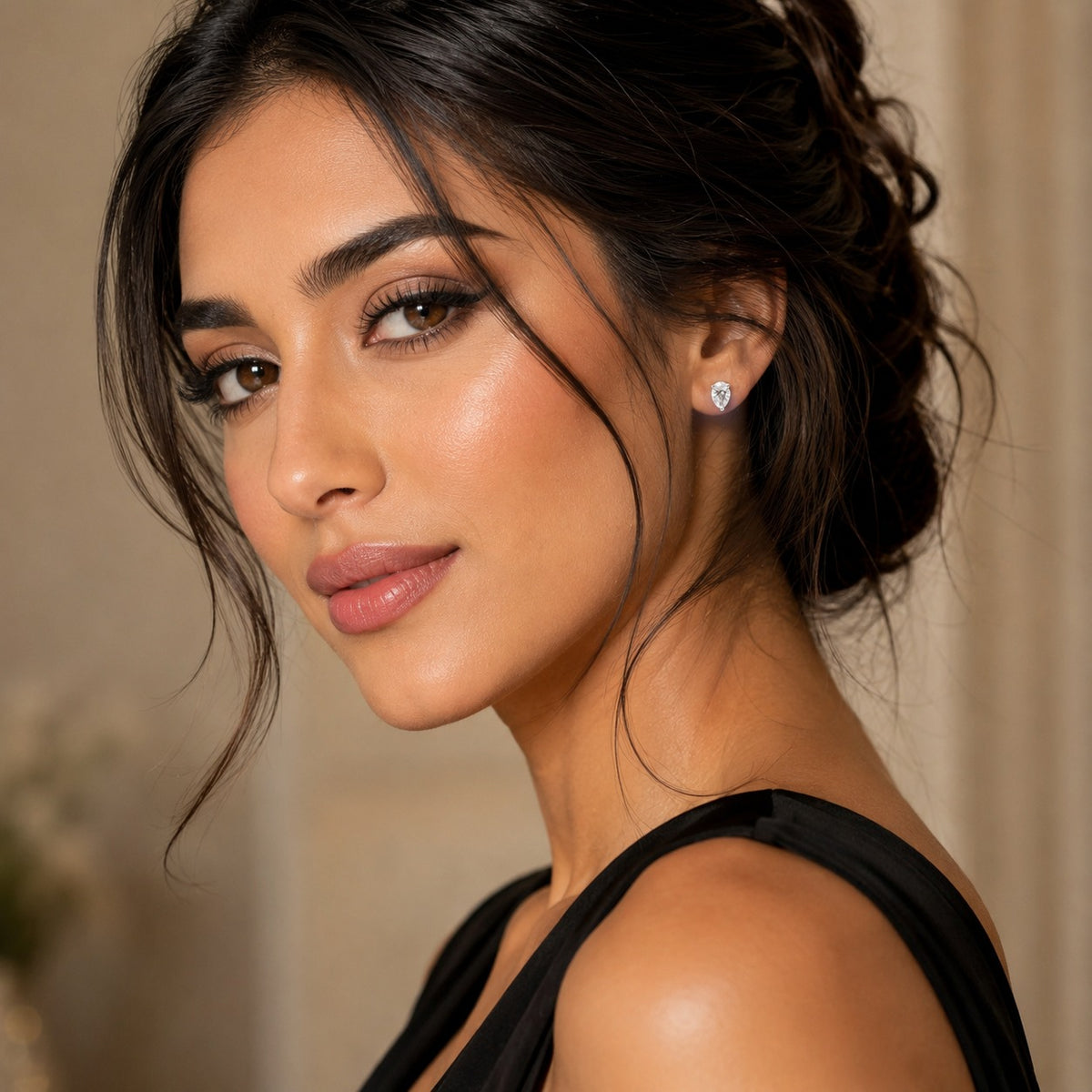 Close-up of a woman with styled hair and earrings against a neutral background
