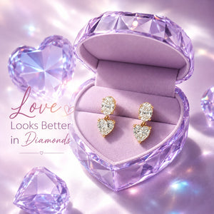 A pair of gold heart-shaped drop earrings with clear gemstones displayed in a purple heart-shaped jewelry box. The image has a romantic, sparkling purple theme with the text 'Love Looks Better in Diamonds' on the left.