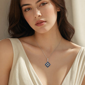 A delicate 14K white gold chain necklace featuring a geometric diamond-shaped pendant adorned with natural blue sapphires and sparkling white diamonds, displayed on a clean white studio background.