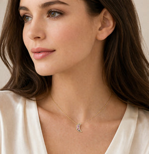 Woman wearing a delicate necklace with a small pendant against a neutral background