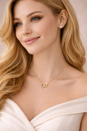 Woman wearing a gold necklace with a heart pendant against a neutral background