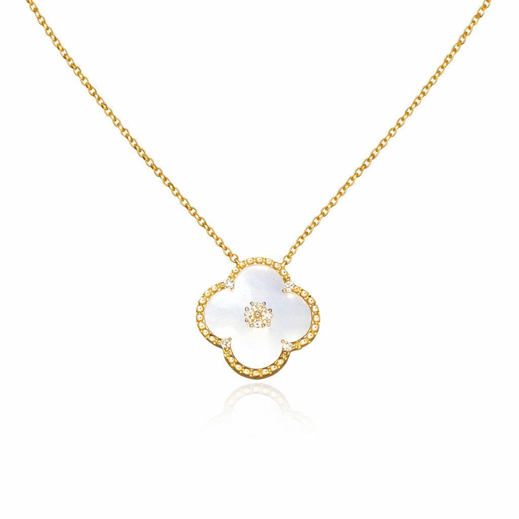 Gold necklace with a white clover-shaped pendant on a white background