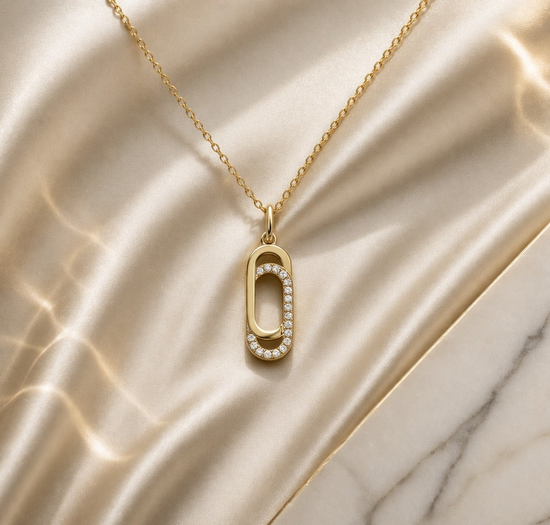 Gold necklace with a unique pendant on a marble surface
