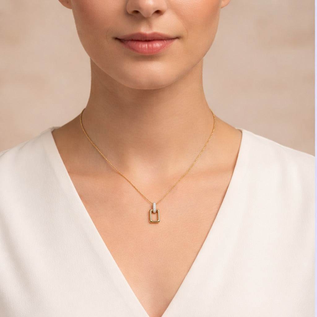 Woman wearing a gold necklace with a small pendant against a neutral background