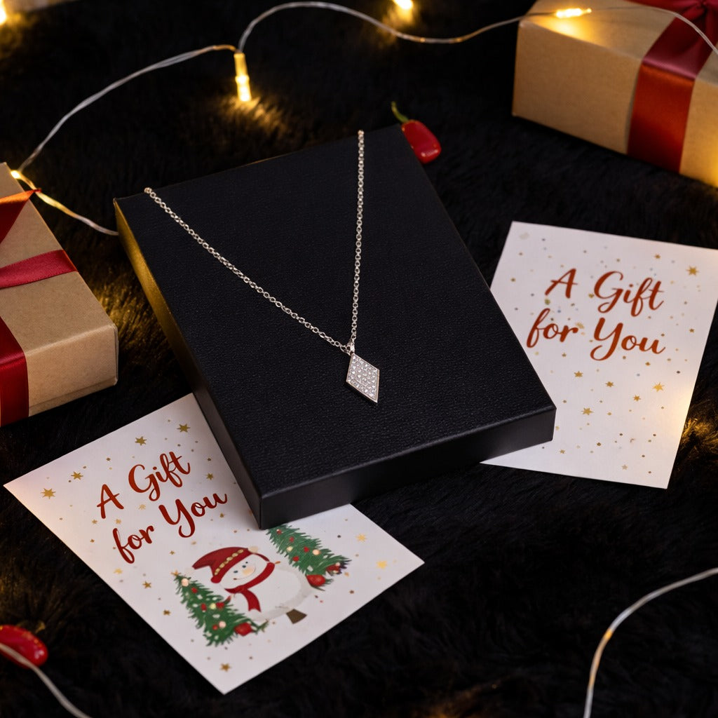 Silver necklace in a black box with 'A Gift for You' cards and Christmas decorations.