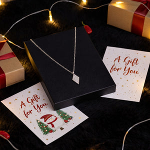 Silver necklace in a black box with 'A Gift for You' cards and Christmas decorations.