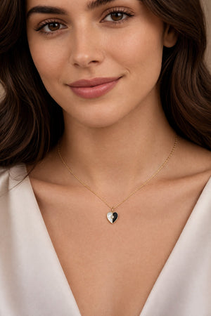 Woman wearing a delicate necklace with a heart-shaped pendant against a neutral background