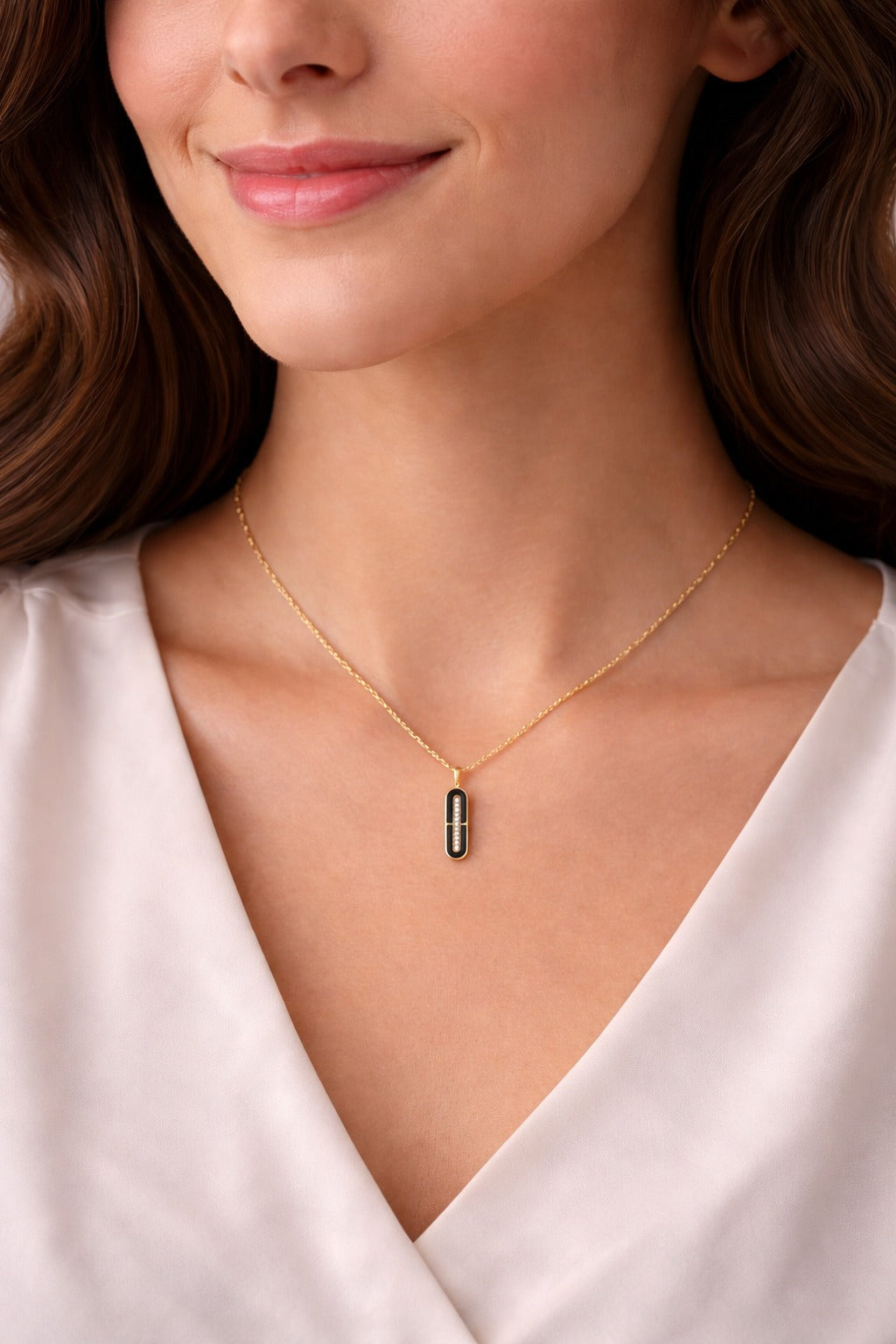 Woman wearing a gold necklace with a small pendant on a white background