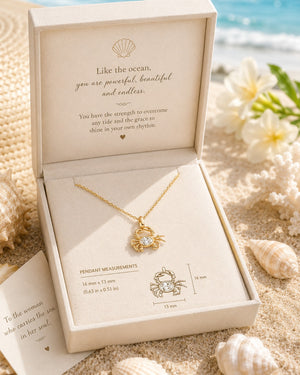 Gold necklace in a jewelry box with ocean-themed message on sand and shells