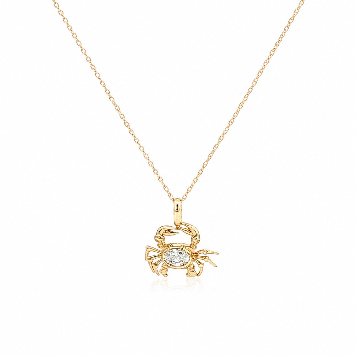 Delicate yellow gold necklace featuring a crab-shaped pendant with a sparkling oval diamond centerpiece, suspended from a fine chain on a light gray background.
