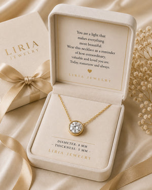Gold necklace in Liria Jewelry box with sentimental message on a beige background