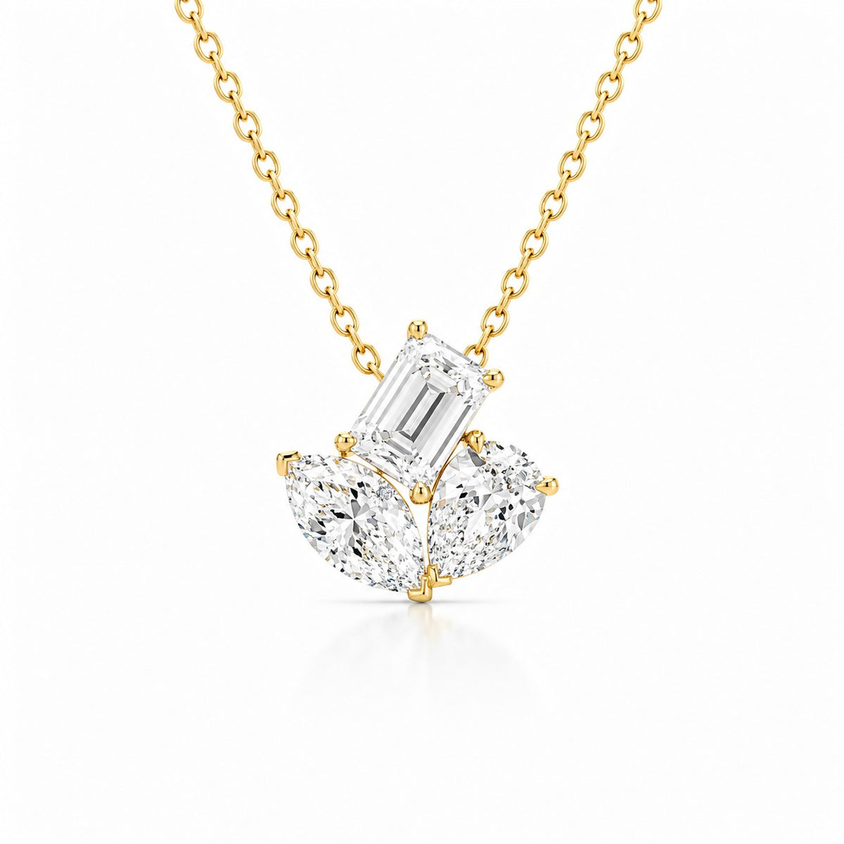 Yellow gold diamond pendant necklace featuring an emerald-cut center diamond accented by two pear-shaped diamonds on a delicate chain, displayed on a light gray background.