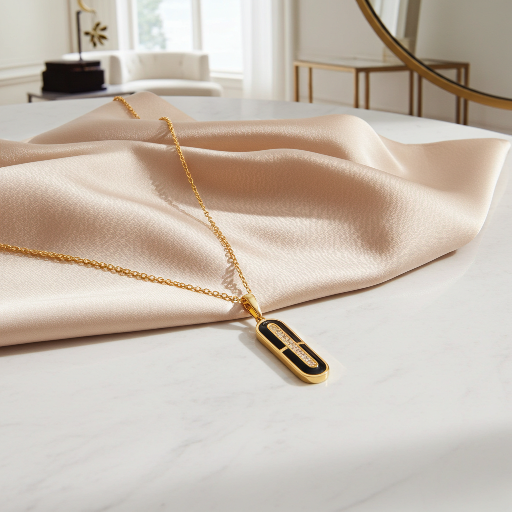 Gold necklace with a pendant on a beige fabric in a softly lit room.